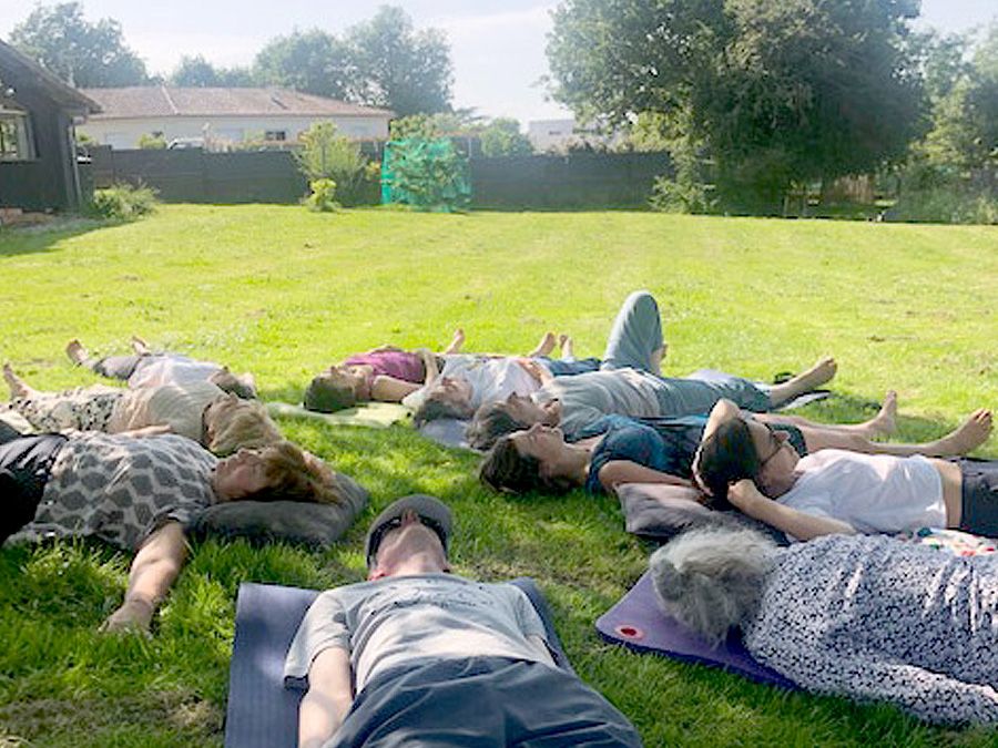 Groupe allongé dans l’herbe lors d’un temps de détente et de présence en pleine nature